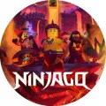 Kulatý jedlý obrázek s třemi nindži a bílým nápisem Ninjago na pozadí lávové jeskyně v oranžových a červených tónech, obrázek na dort