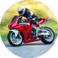 Červená sportovní motorka v zatáčce s jezdcem v kombinéze na rozmazaném zeleném pozadí, jedlý obrázek na dort