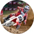 Jezdec na červenobílé motorce v zatáčce motokrosové tratě, za ním odletuje písek, jedlý obrázek na dort