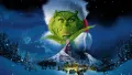 Zelený Grinch v mikulášské čepici shlíží na zasněžený kopec a městečko Kdovíkov v noci, jedlý obrázek na dort