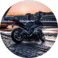 Černá sportovní motorka na nábřeží při západu slunce s mostem v pozadí, jedlý obrázek na dort