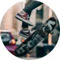 Kulatý jedlý obrázek na dort: skateboardista ve výskoku, sportovní tenisky a rozmazaná městská ulice v teplém světle