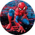 Spiderman v dřepu u cihlové zdi s červenými a modrými cákanci barvy, kulatý jedlý obrázek na dort
