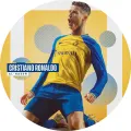 Kulatý jedlý obrázek fotbalisty v žluto-modrém dresu Al-Nassr klečícího po gólu na žlutém pozadí s pruhy, jedlý obrázek na dort