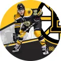 Hokejista Pastrňák v žluto-černém dresu číslo 88 na kulatém jedlém obrázku na dort, s logem Bostonu v pozadí.