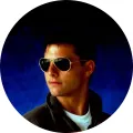 Kulatý jedlý obrázek na dort s mladým pilotem v letových brýlích a bundě na modrém pozadí, motiv z filmu Top Gun