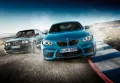 Modré BMW M2 a tmavě modré M3 v zatáčce závodního okruhu s prachem za koly, jedlý obrázek na dort