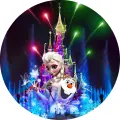 Kulatý jedlý obrázek na dort: Elsa a Olaf v popředí, za nimi zámek s barevným ohňostrojem na noční obloze, jedlý obrázek na dort