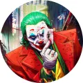 Joker v červeném obleku se zelenými vlasy a hrací kartou v ruce na tmavém městském pozadí, jedlý obrázek na dort