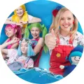 Kulatý jedlý obrázek na dort: čtyři dívky Lollipopz v žluté, růžové, zelené a modré paruce a blondýnka s modrou panenkou na hladině