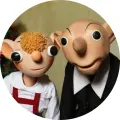 Kulatý jedlý obrázek na dort se Spejblem v tmavém obleku a Hurvínkem s zrzavou čupřinou a červenými šlemi vedle sebe