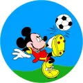 Mickey Mouse v červeno-žlutém dresu kope do fotbalového míče na zeleném trávníku pod modrou oblohou, jedlý obrázek na dort