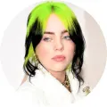 Kulatý portrét Billie Eilish se zelenými a černými vlasy, v bílém huňatém kabátu na krémovém pozadí, jedlý obrázek na dort