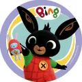 Černý králíček Bing v červeno-žlutém oblečení drží plyšového Hopíka na kulatém jedlém obrázku s tyrkysovým pozadím, jedlý obrázek na dort