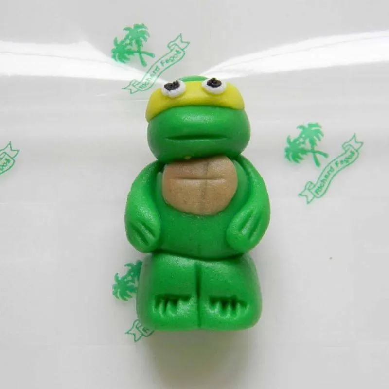 Jedlá figurka želvy Ninja Michelangelo z kokosové hmoty o velikosti 5 cm na zdobení dortů